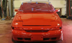 Roter Sportwagen in der Werkstatt, bereit für die Lackierung. Die Frage "was kostet eine Lackierung?" beschäftigt den Besitzer.