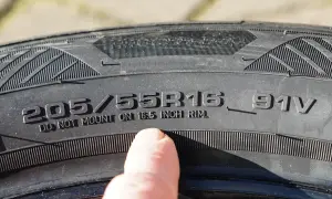Ein Finger zeigt auf die Reifengröße 205/55R16, um die Zoll-Angabe abzulesen.