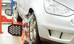 Ein Auto wird auf einer Hebebühne für die vorspur einstellen vorbereitet. Messgeräte sind an den Rädern angebracht.