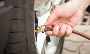 Hand befestigt Schlauch an Reifenventil für den Reifendruck am Auto.