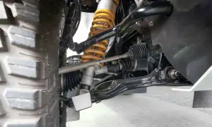 Detailaufnahme der Radaufhängung eines Fahrzeugs. Ein defekter Querlenker kann sich durch Geräusche und schlechtes Fahrverhalten bemerkbar machen.