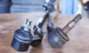 Zwei Spurstangenköpfe liegen nebeneinander. Einer ist neu, der andere ist stark abgenutzt und zeigt, dass der spurstangenkopf ausgeschlagen ist.