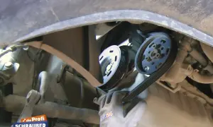 Ein Mechaniker wechselt einen Keilriemen. Die Keilriemen wechseln Kosten sind oft überschaubar.