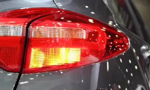 Rücklicht eines Autos, der Blinker blinkt schnell. Reflektionen auf dem grauen Lack.