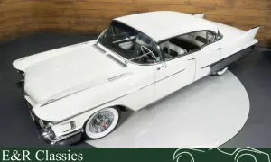 Ein weißer Cadillac mit Heckflossen steht auf einem Drehteller. Dieses klassische Auto strahlt Eleganz aus.