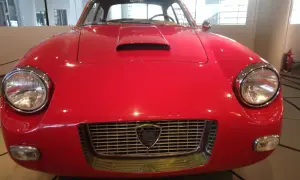 Vorderansicht eines roten italienischen Oldtimers mit Lancia-Logo im Kühlergrill.