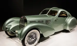 Ein alter Bugatti in pastellgrün, ein Meisterwerk der Automobilgeschichte mit geschwungenen Linien und Speichenrädern.