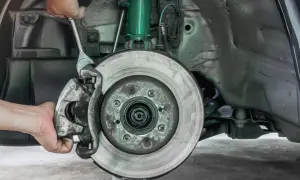 Mechaniker wechselt Bremssattel. Informieren Sie sich über die Bremsen wechseln Kosten für Ihr Fahrzeug.