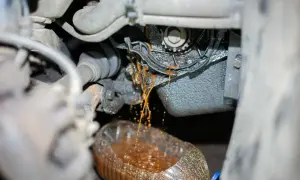 Flüssigkeit tropft aus der defekten Wasserpumpe eines Autos in einen Behälter.