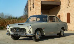 Eine elegante Lancia Flaminia Coupé steht vor einem Backsteinhaus.