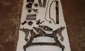 Rostige Autoteile, Federn und Querlenker liegen auf einem weißen Tuch. Die auto sandstrahlen kosten sind hier ein wichtiger Faktor für die Aufbereitung.