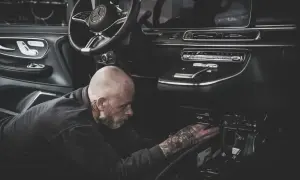 Ein Mechaniker mit Tattoos repariert den Anlasser eines modernen Autos.