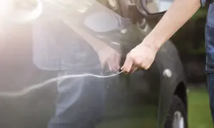 Person versucht, einen Kratzer am Auto mit einem Werkzeug auszubessern.