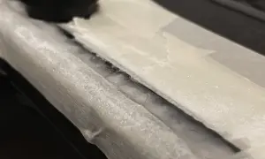 Detailaufnahme: Riss in einem Bakelit-Teil, der mit Klebeband abgedeckt ist. Ein schwarzer Drehknopf ist im Hintergrund zu sehen. Hier wird Bakelit reparieren.