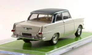 Ein cremefarbener Opel Rekord 1960 als Modellauto mit dunkelgrünem Dach, auf einer grünen Unterlage.