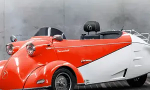 Ein leuchtend rotes und weißes Messerschmitt Auto mit Retro-Charme steht vor einer Betonwand.