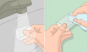 Hände reinigen ein Bakelit-Objekt unter fließendem Wasser und trocknen es dann mit einem Tuch.