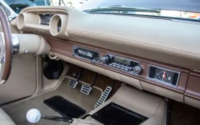 Armaturenbrett eines Oldtimers mit altem Autoradio. Mit einem Adapter lässt sich das alte Autoradio mit dem Handy verbinden, um Musik zu hören.