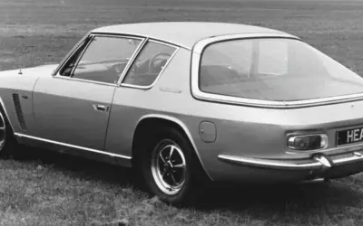 Ein Jensen Interceptor Auto steht auf einer Wiese. Das Heck des Wagens mit dem Kennzeichen "HEA ID" ist zu sehen.
