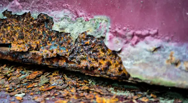 Stark verrostete Kante mit abgeblätterter roter Farbe. Ein Beispiel für entrosten mit Essig und Backpulver.