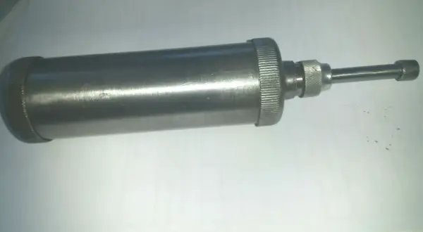 Metallische Handfettpresse mit gerändeltem Griff und Auslauf, ein Beispiel für verschiedene Schmiernippel Arten.