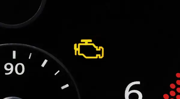 Gelbes Motorzeichen leuchtet auf dem Armaturenbrett eines Autos auf. Es ist Zeit, die Werkstatt zu besuchen.