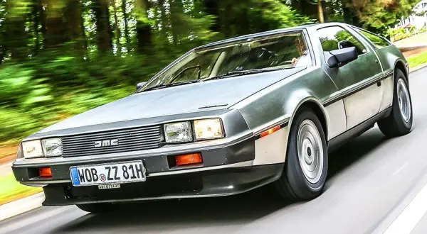 Silberner DeLorean DMC-12 rast durch eine grüne Allee.