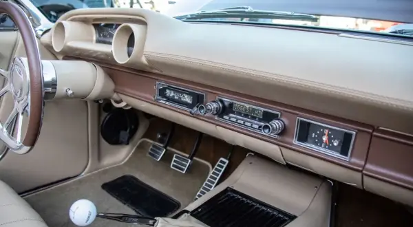 Armaturenbrett eines Oldtimers mit altem Autoradio. Mit einem Adapter lässt sich das alte Autoradio mit dem Handy verbinden, um Musik zu hören.