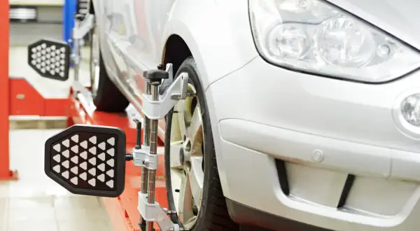 Ein Auto wird auf einer Hebebühne für die vorspur einstellen vorbereitet. Messgeräte sind an den Rädern angebracht.