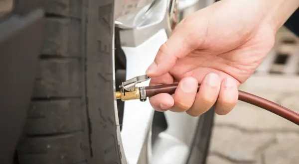 Hand befestigt Schlauch an Reifenventil für den Reifendruck am Auto.