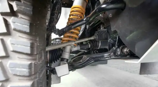 Detailaufnahme der Radaufhängung eines Fahrzeugs. Ein defekter Querlenker kann sich durch Geräusche und schlechtes Fahrverhalten bemerkbar machen.