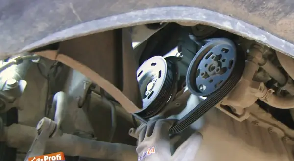 Ein Mechaniker wechselt einen Keilriemen. Die Keilriemen wechseln Kosten sind oft überschaubar.