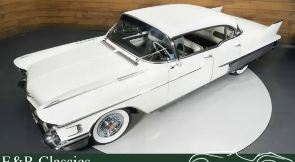 Ein weißer Cadillac mit Heckflossen steht auf einem Drehteller. Dieses klassische Auto strahlt Eleganz aus.
