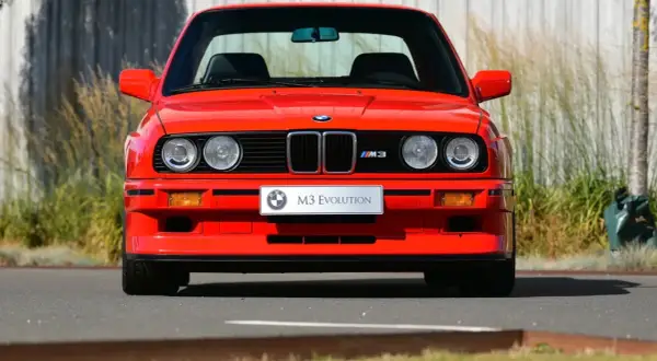 Roter BMW E30 M3 Evolution, ein Klassiker aus den 80ern, steht im Freien.