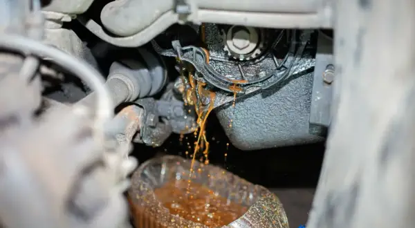 Flüssigkeit tropft aus der defekten Wasserpumpe eines Autos in einen Behälter.
