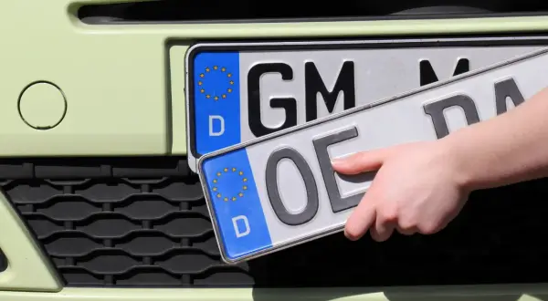 Hand wechselt Kennzeichen. Vorbereitung zum auto ummelden.