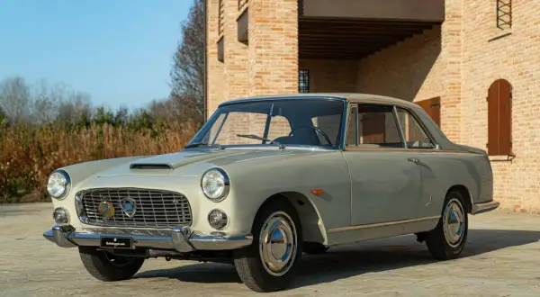 Eine elegante Lancia Flaminia Coupé steht vor einem Backsteinhaus.