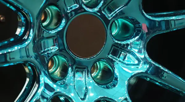 Glänzende Felgen, frisch lackiert in einem auffälligen Türkis. Die Spiegelung des Lichts auf der glatten Oberfläche lässt die Felgen fast lebendig wirken.