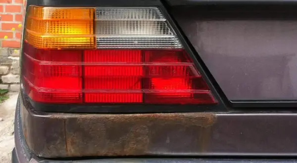 Rost unter Lack am Heckleuchtenbereich eines Autos. Zeit, den Rost unter Lack zu entfernen und das Fahrzeug zu retten.