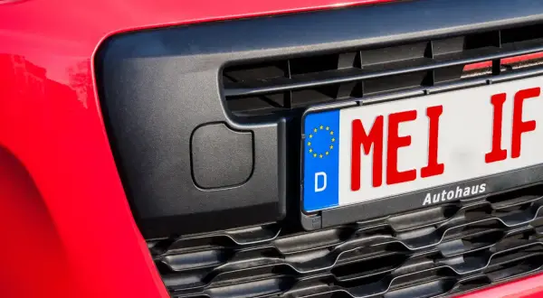 Rotes Kennzeichen "MEI IF" an einem roten Auto, bereit für das Fahrtenbuch.