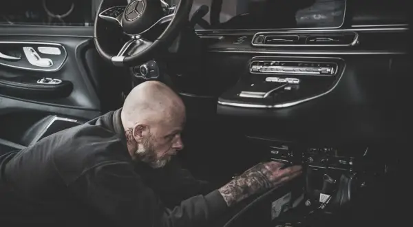 Ein Mechaniker mit Tattoos repariert den Anlasser eines modernen Autos.