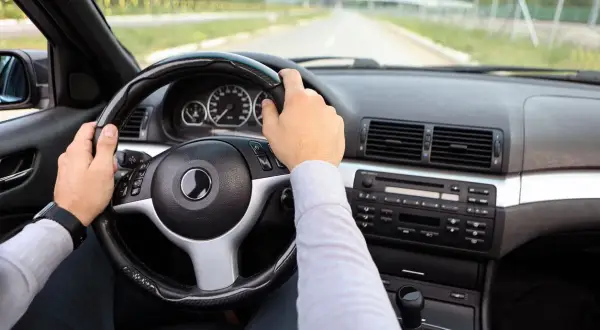 Fahrer hält das Lenkrad, das leicht schief steht. Ein Hinweis, dass das Lenkrad schief selber einstellen nötig sein könnte.
