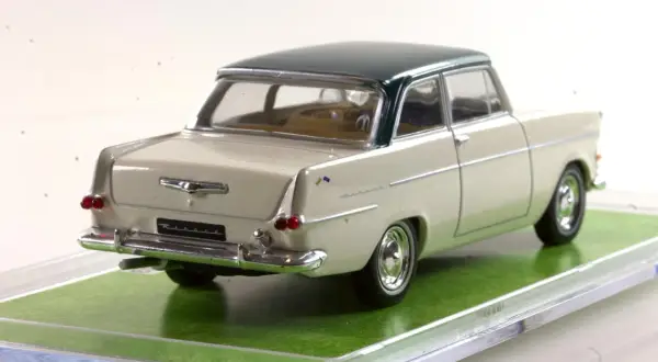 Ein cremefarbener Opel Rekord 1960 als Modellauto mit dunkelgrünem Dach, auf einer grünen Unterlage.