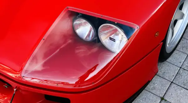 Der rote Ferrari f40 lm mit seinen charakteristischen Scheinwerfern unter einer transparenten Abdeckung.