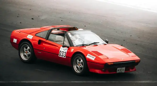 Roter Ferrari 308 GTB mit Startnummer 033 auf der Rennstrecke, bereit für die nächste Runde.