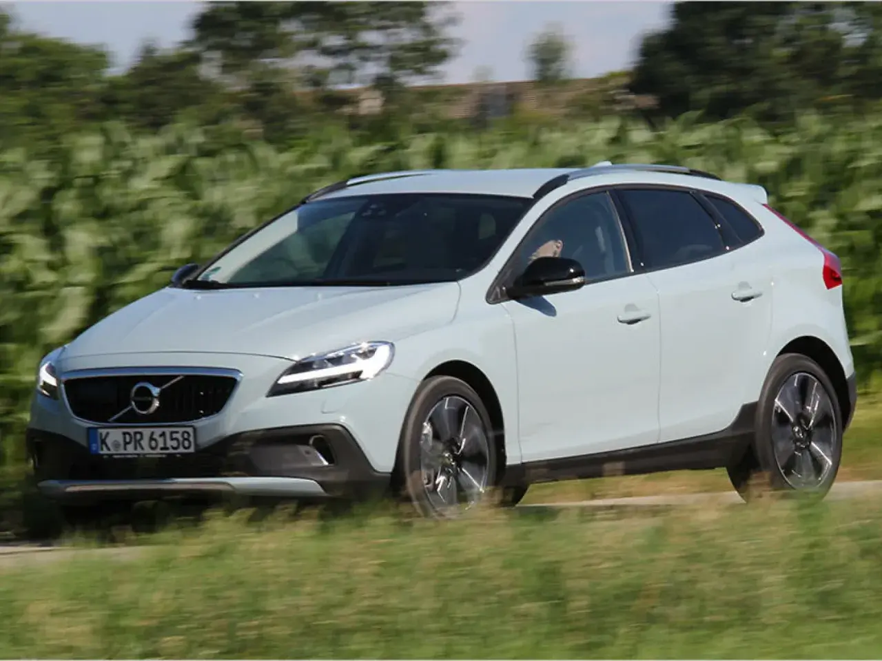 Ein hellblauer Volvo V40 Cross Country fährt auf einer Landstraße.