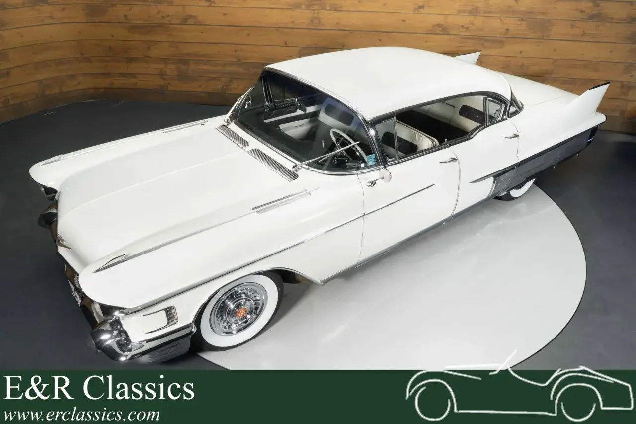Ein weißer Cadillac mit Heckflossen steht auf einem Drehteller. Dieses klassische Auto strahlt Eleganz aus.