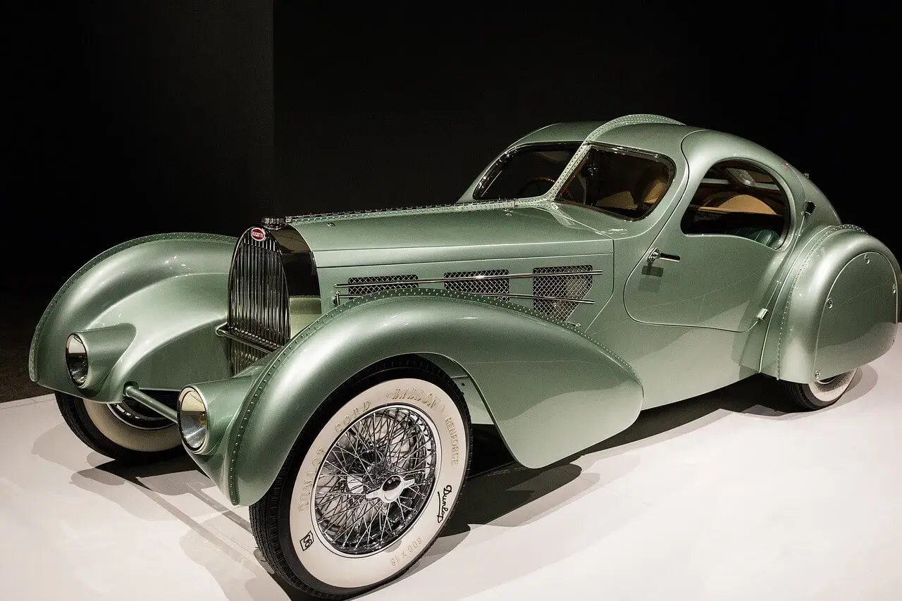 Ein alter Bugatti in pastellgrün, ein Meisterwerk der Automobilgeschichte mit geschwungenen Linien und Speichenrädern.