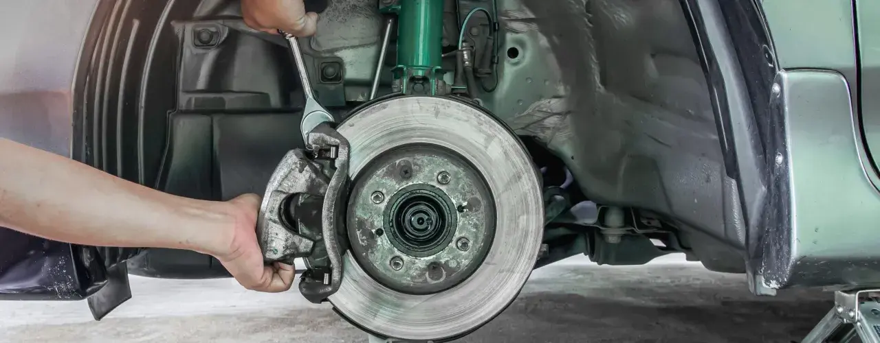 Mechaniker wechselt Bremssattel. Informieren Sie sich über die Bremsen wechseln Kosten für Ihr Fahrzeug.