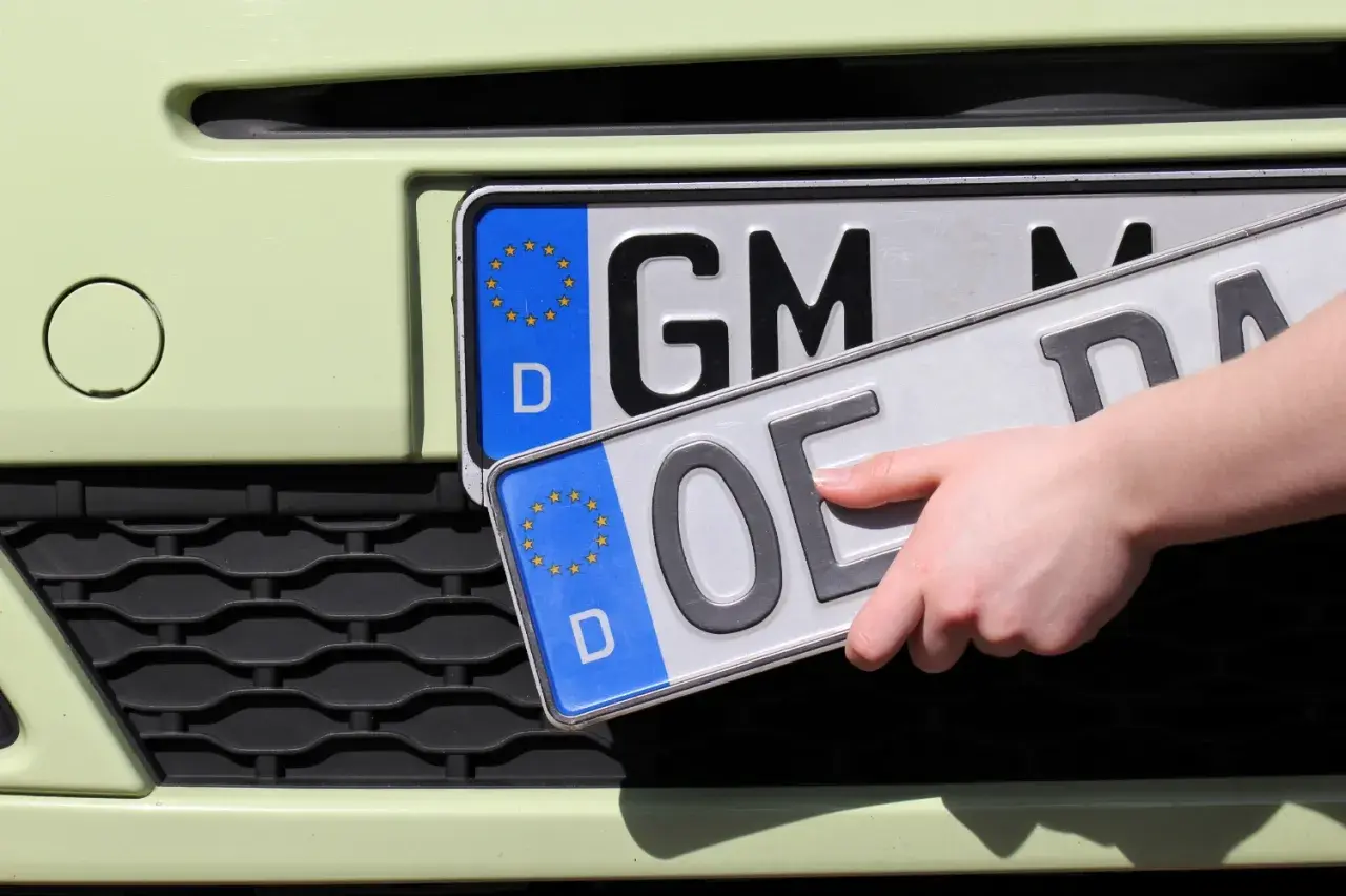 Hand wechselt Kennzeichen. Vorbereitung zum auto ummelden.